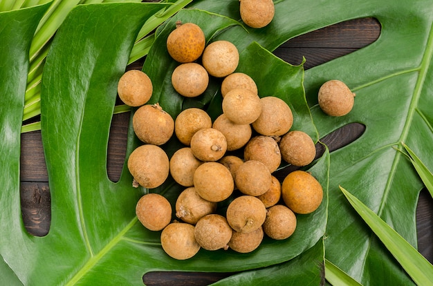 Exotisch fruitLongan, Lam-yay of Dragon&#39;s Eye. Verschillende soorten fruit op monstera en palmbladeren.