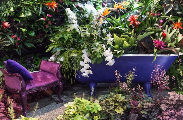 Exotische, tropische bloemen en groen in een paarse badkuip.