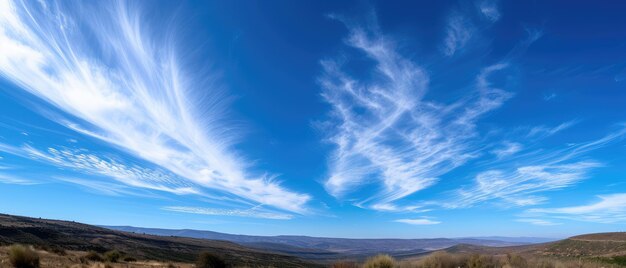 景色 の 丘 の 上 に 広がっ て いる 青い 空 と 羽 の よう な 雲