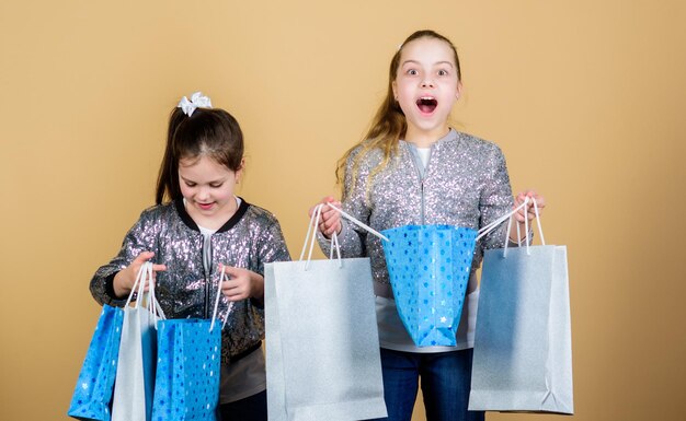 Expect more Pay less Girls sisters friends with shopping bags beige background Shopping and purchase Black friday Sale and discount Shopping day Children hold bunch packages Kids fashion