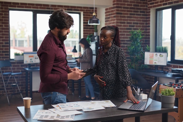 Donna di affari in attesa che utilizza un computer moderno per rivedere la politica di lavoro della società di avvio. ufficio di agenzia multiculturale e diversificato che parla di strategie redditizie e portafoglio di partner.