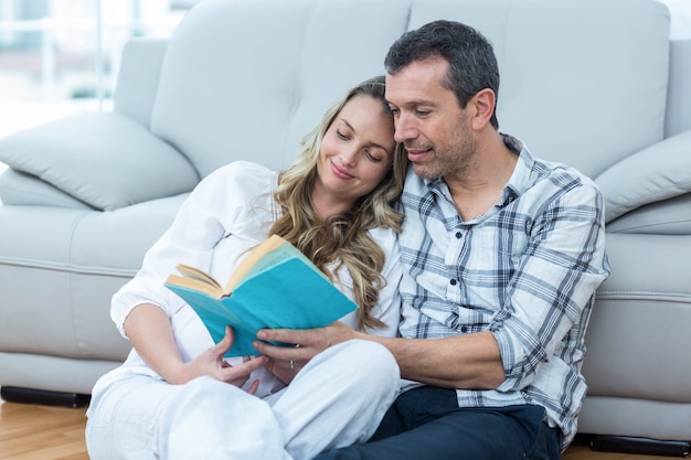 Expecting couple sitting on floor and reading book