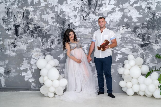 In expecting. Happy pregnant pair in fashion clothes posing in studio