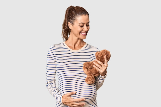 Photo expecting middleaged woman holding plush toy in studio