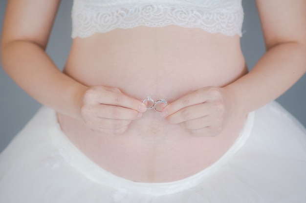 An expecting mother holding wedding ring. pregnant woman