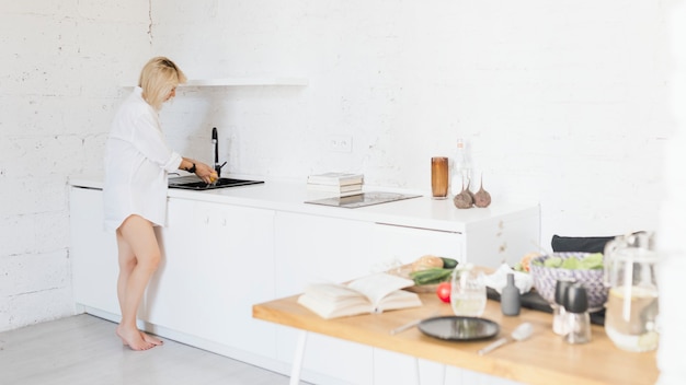 Photo expecting mother washing dishes in the kitcheb