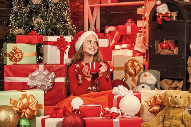 Ожидание рождественской распродажи Санта-Клауса Помощник Санты пьет молоко улыбающийся продавец в шляпе Санты со множеством подарочных коробок успешный шопинг на рождественском рынке, украшенный подарочным пакетом для покупок