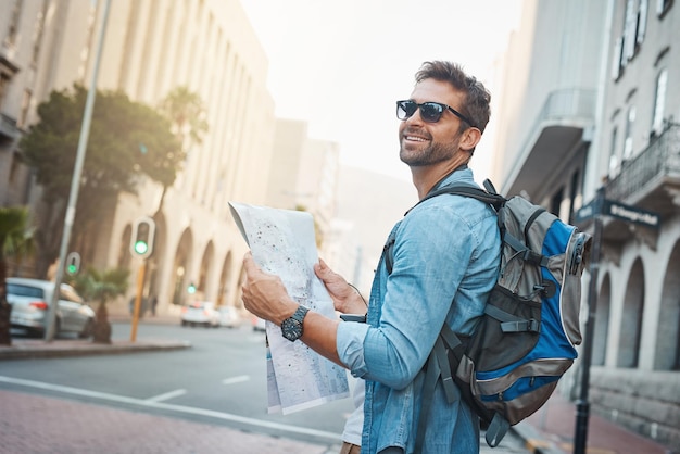 世界の自然文化と人工の驚異を体験してください外国の都市を旅行しながら地図を見ている若い男のショット