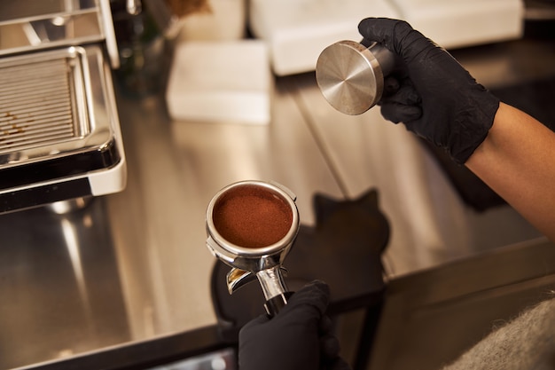 Experienced barista making coffee pad while working