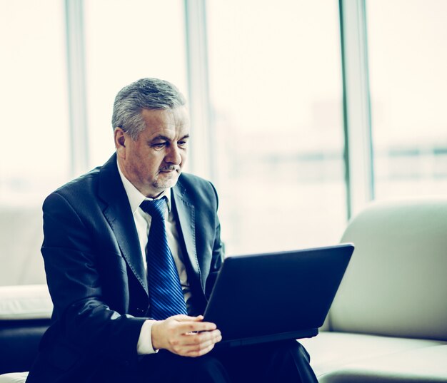 Experienced businessman working on laptop sitting on sofa in a p