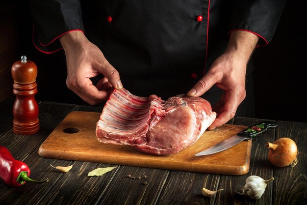 経験豊富なシェフがキッチンで骨付きの生肉を持っています