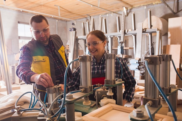 Experienced craftsman teaching female apprentice to work with\
woodworking machinery