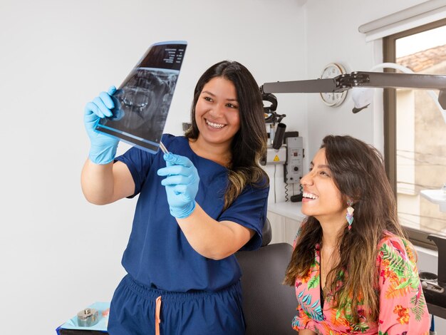 An experienced dentist smiles at her patient in the office while showing a panoramic Xray