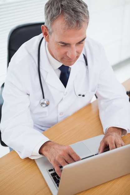 Experienced doctor typing on his laptop