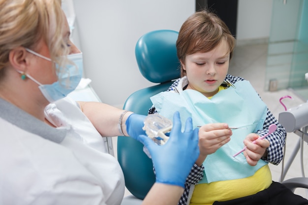 Experienced female dentist checking teeth of young boy