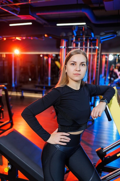 Un esperto istruttore di fitness di una donna sportiva si trova in palestra e pensa a un piano di esercizi. dieta e concetto di perdita di peso. personal trainer donne in palestra