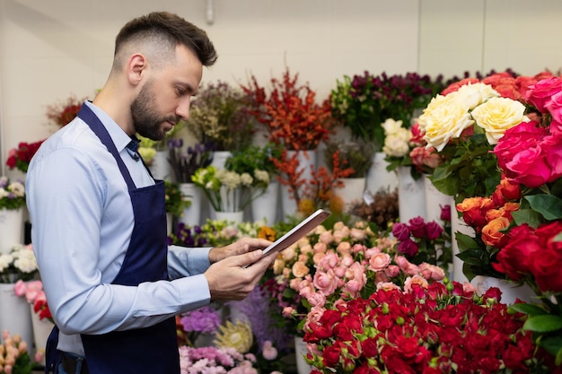 冷蔵庫の中の花の間にクリップボードを持った経験豊富な花屋。