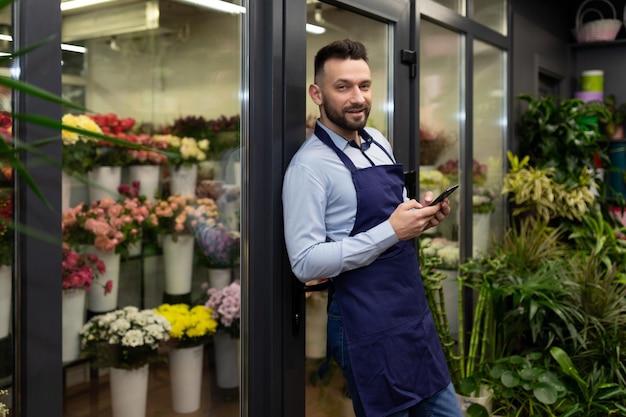 Experienced male florist on the background of the refrigerator with fresh bouquets