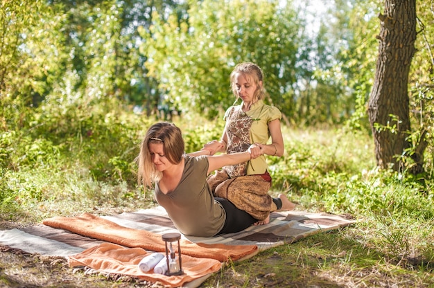 Experienced masseuse applies her massage skills on her client on the ground