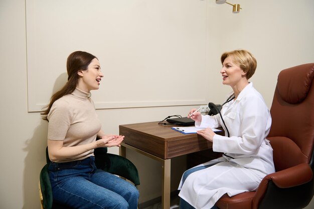 Experienced mature female doctor writes down the patient\'s\
complaints fills out a medical card during an appointment in office\
in a general hospital