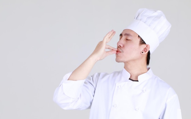 経験豊富で賢い中国人シェフがエレガントな料理の制服を着て笑顔で自信を持ってキッチンに立って腕を組んで豪華な食事の資格のある料理の専門家として