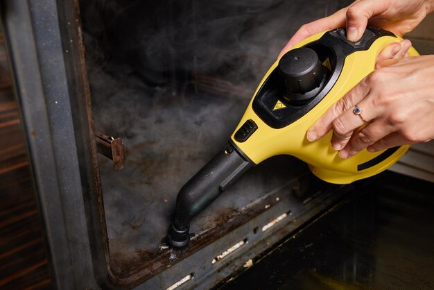 ゴム手袋の経験豊富な労働者は、厨房機器を蒸気洗浄します