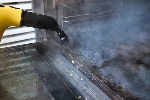 Foto lavoratore esperto di guanti di gomma per la pulizia a vapore delle attrezzature da cucina