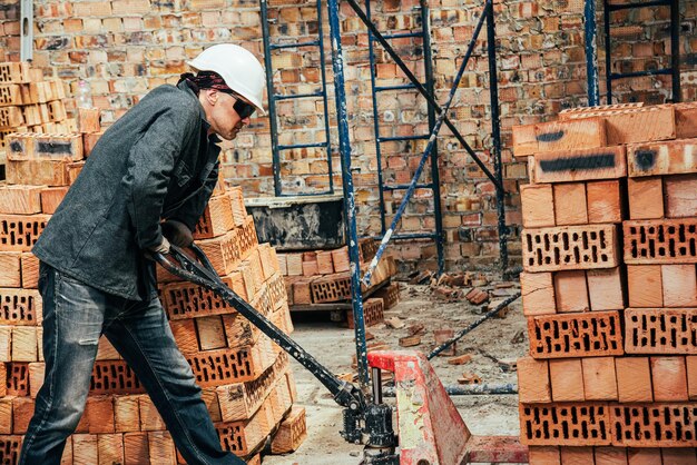 Photo an experienced worker works on the construction of a brick house