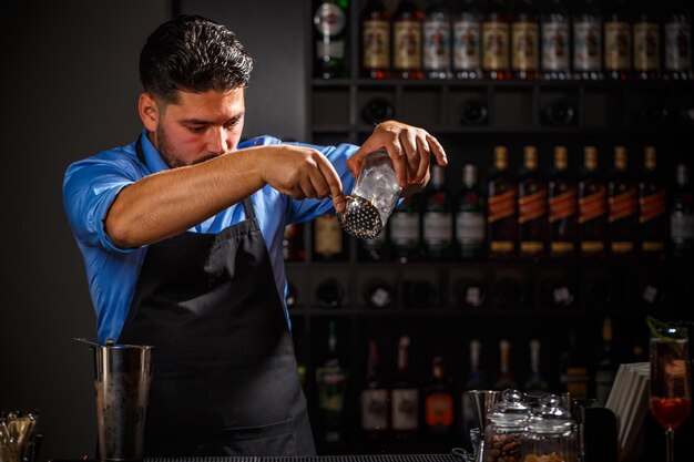 Expert barman is making cocktail