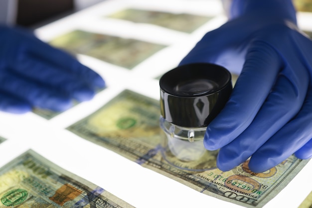 Expert checks authenticity of banknotes. Counterfeiting and types of fraud concept