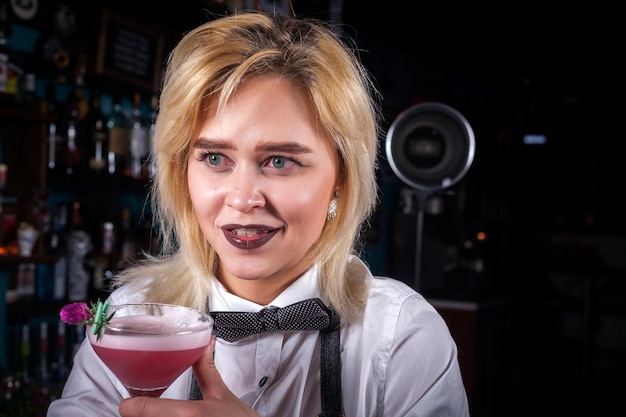 Expert girl bartending demonstrates the process of making a cocktail at the night club