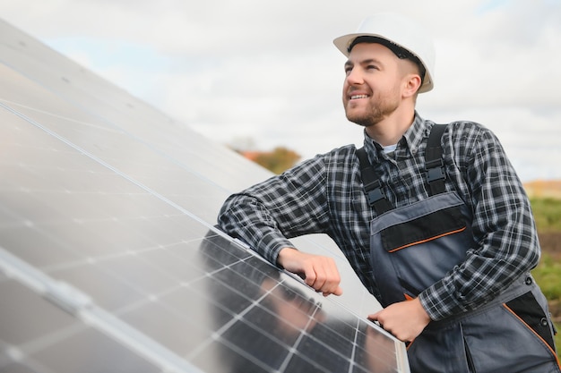 Expert is inspecting quality of a solar batterys Worker in uniform and helmet with equipment Ecology power conservation concept