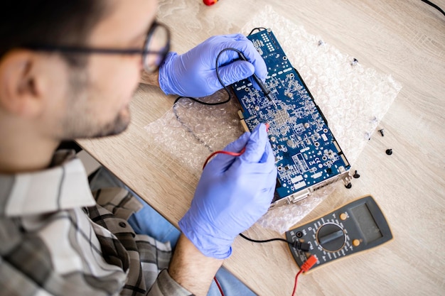 An expert repairing electronic device and checking voltage of motherboard in computer service