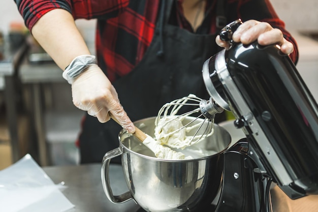 Photo a expert wearing red plaid shirt black apron and transparent gloves stiring dough with wooden spoon