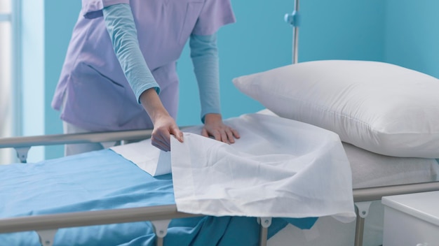 Expert young nurse making the bed at the hospital