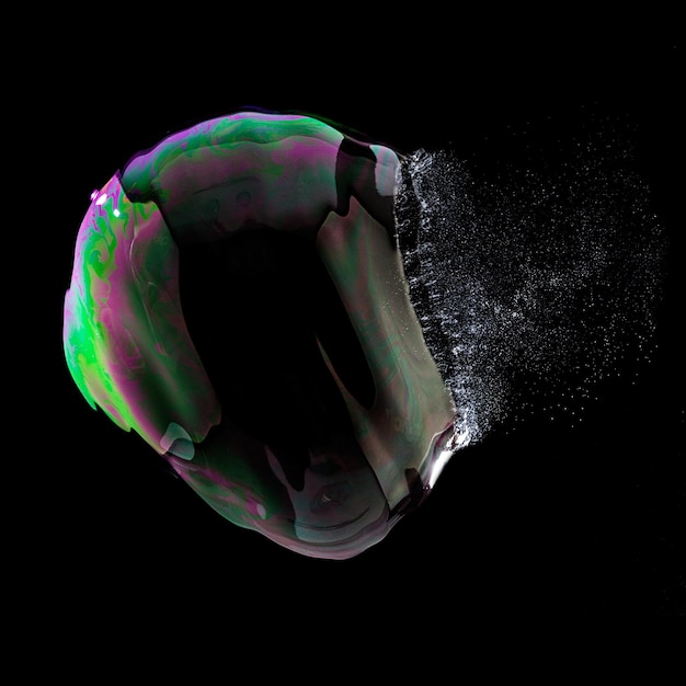 Взрыв мыльного пузыря в красочных цветах на черном фоне