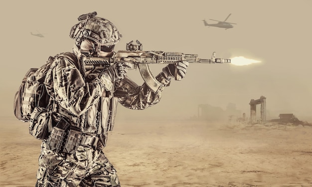 Exploitant van Russische speciale operatietroepen met een kalashnikov-aanvalsgeweer, een militaire rugzak en een gevechtshelm die een wapen afschiet in de woestijn in Syrië. Oude ruïnes en helikopters