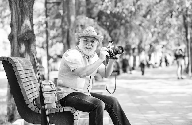 Explore city Tourism hobby Tourist concept Travel and tourism Photographer sit on bench in park Capturing spring beauty Enjoying free time Walking his favorite street Senior man hold camera