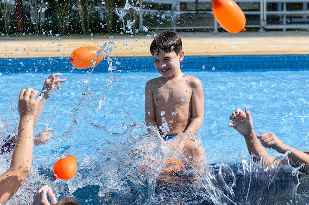 Explosion of water. Defocused in the background, smiling 8 year old child sitting on the edge of the pool.