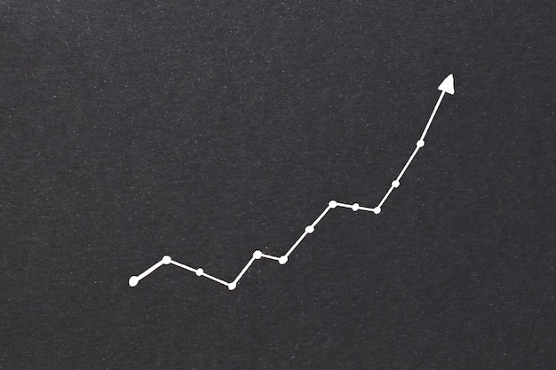 写真 指数関数的な図の傾向の成功の増加と黒い紙の背景に上向きの財務予測の概念の矢印
