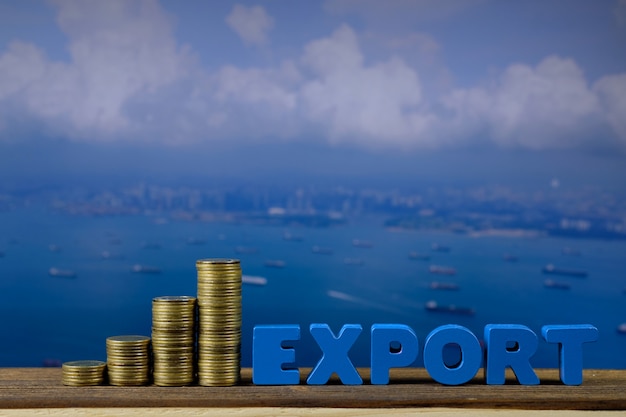 EXPORT text and stack of coin on wood with seascape and cargo ship background