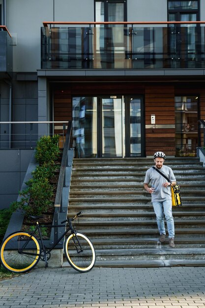 Expresbezorger met geïsoleerde tas de trap af naar zijn fiets