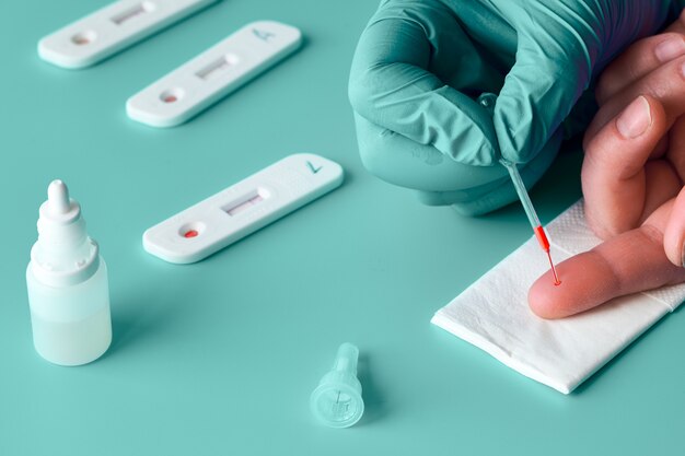 Photo express covid-19 test for igm and igg antibodies to novel coronavirus sars-cov-2, covid-19. nurse hand in nitril glove collects patient blood with pipette. gren mint turquoise background, copy-space.