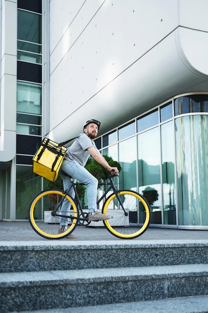 Express delivery courier standing on bicycle with insulated bag