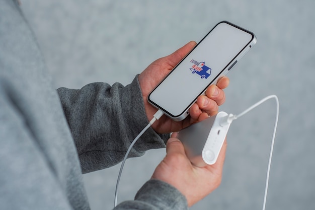 Express delivery in your phone. A man holds a smartphone with power bank and icon on a white screen in his hands.