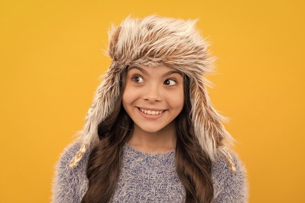 Express positive emotion winter fashion happy kid with curly hair in earflap hat