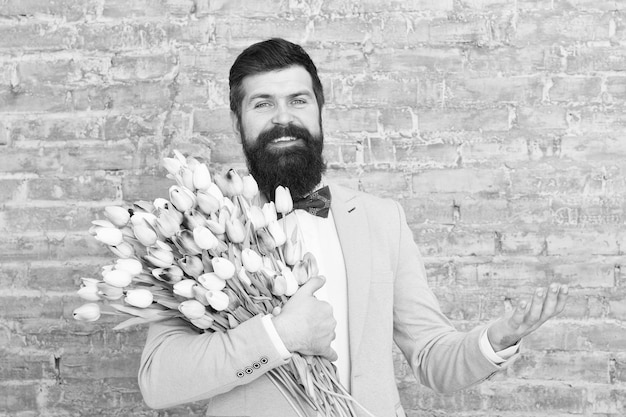 Foto esprimi positività felice giorno della donna fiore per l'8 marzo regalo di primavera felice uomo barbuto hipster con fiori copia spazio barbuto uomo felice con bouquet di tulipani data d'amore felice vacanza