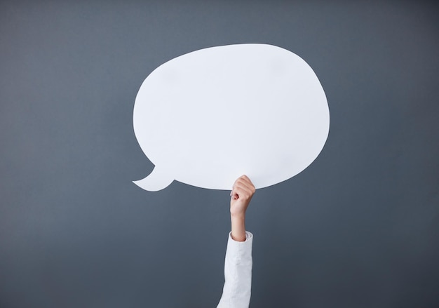 Express your message on here Studio shot of an unrecognizable businesswoman holding up a white speech bubble against a gray background