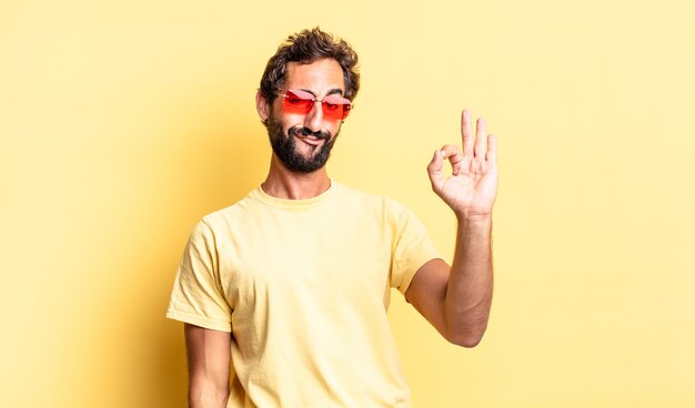Expressieve gekke bebaarde man met een zonnebril met een kopieerruimte tegen de gele muur