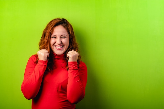 Foto expressieve gelukkige roodharigevrouw op groene achtergrond